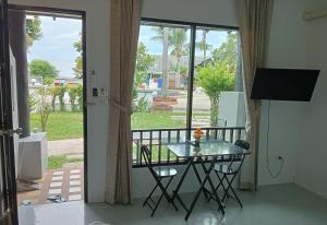 a glass table and chairs in a room with a balcony at Sirimaya Garden Home & Residence in Bang Rak Beach