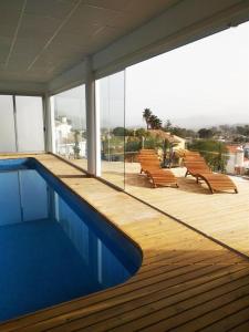 a swimming pool on a building with benches and a deck at Villa Fenix in Gandía