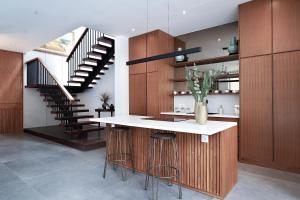 a kitchen with a counter with stools and a staircase at Villa Mamakami - 3BR Luxury Villa in Canggu in Canggu