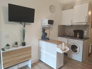 a kitchen with a washing machine and a tv at studio cabine avec véranda et terrasse in Luchon