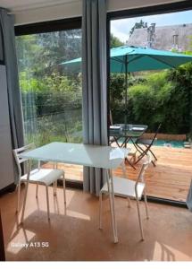 a table and two chairs and an umbrella on a patio at studio cabine avec véranda et terrasse in Luchon