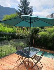 a table and chairs under an umbrella on a deck at studio cabine avec véranda et terrasse in Luchon