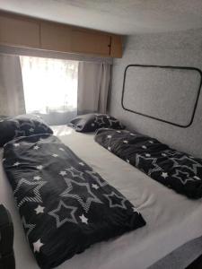 a bed with black and white sheets and pillows on it at Bungalow in Göhren auf Rügen direkt am Strand in Göhren