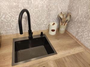 a kitchen counter with a sink and a cup of utensils at Bungalow in Göhren auf Rügen direkt am Strand in Göhren