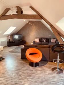a living room with a couch and an orange chair at CHAMBRE et JARDIN Village au bord de l eau Cour et Garage privés in Marcilly-sur-Seine