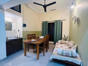 a dining room with a table and a kitchen at Meadows Serene Retreat in Kannur