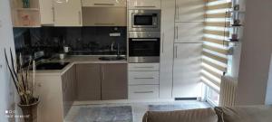 a kitchen with white cabinets and stainless steel appliances at Apartman Iris in Tuzla