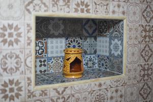 a small niche in a tiled wall with a jar on a shelf at Riad Dar Afram in Essaouira