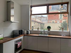 a kitchen with white cabinets and a large window at CHTX Hôtel particulier Albert Ier in Châteauroux