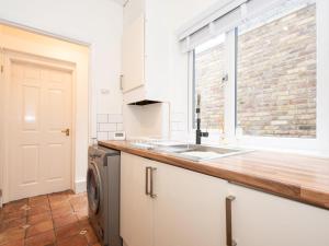 a kitchen with a sink and a washing machine at Quaint Victorian Cottage great transport to London Pass The Keys in Teddington +35 photos