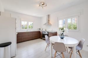 Una cocina y un comedor con una mesa y sillas blancas. en G-Fast fertig gestelltes Inserat- Moderne grosse Villa, 5 Min fussläufig zum Strand,Pool,Klima, en Calas de Mallorca