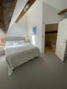 a white bedroom with a large bed and a bathroom at Cosy flat in Ampney Crucis in Ampney Crucis