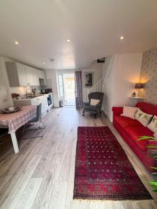 a living room with a red couch and a kitchen at Cosy flat in Ampney Crucis in Ampney Crucis +20 photos