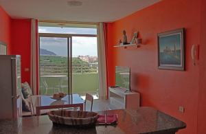 una sala de estar con una pared de color naranja con una mesa y una ventana en Puerto Naos Apartment, en Puerto Naos
