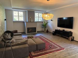 a living room with a couch and a flat screen tv at Klimaanlage, 5 Sterne Villa Bahnhoftraum, plus NEU zubuchbares Event, 333 qm, 1200qm Garten, virtueller Rundgang, Dachterrasse, Whirlpoolbadewanne in Braunfels