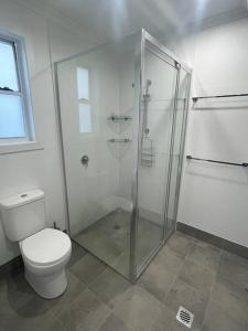 a bathroom with a toilet and a glass shower at New 3 bedroom house in Cooma in Cooma