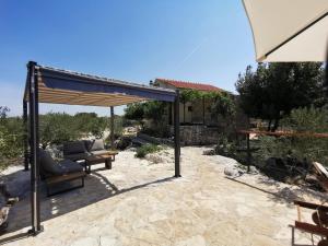a patio with a couch under a pergola at Robinson crusoe style house "MASLINA'' in Škrip