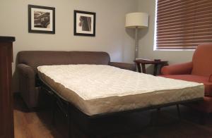 een bed in een kamer met een bank en een stoel bij Affordable Suites of America Portage in Portage