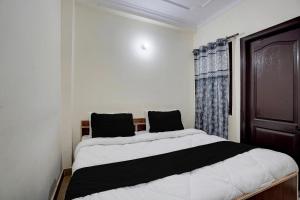a bedroom with a large bed with black and white sheets at Hotel O Peaceful Paradise in New Delhi