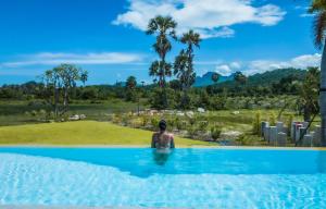 a man in a swimming pool looking at a field at Baan Mahasamut Pranburi in Sam Roi Yot