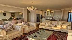 a living room with couches and a table and a kitchen at Bloubergstrand Beachfront Apartment Witsand 101 Tablemountain and ocean views in Cape Town