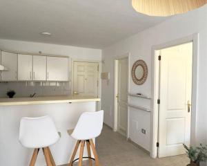eine Küche mit zwei weißen Stühlen und einer Theke in der Unterkunft Apartamento con Vista al mar y piscina en Puerto Santiago Tenerife in Puerto de Santiago