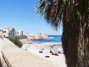 a beach with many people with umbrellas and the ocean at Casa Argentieri 3 in Trapani