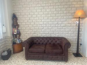 a brown couch sitting against a white brick wall at Hostal Moreno in Silla