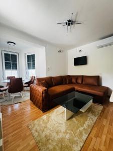 a living room with a brown couch and a table at Residence La Femme in Tuzla