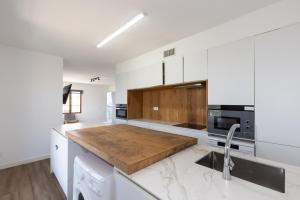 a kitchen with white cabinets and a wooden counter top at PANORAMIC VILLA x in Salou