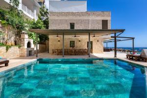 an outdoor swimming pool with a villa in the background at Villa Korsan- 8 Bedroom Villa with Private Pool and Sea View in Kas
