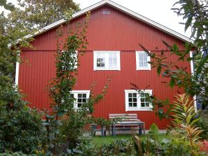 un granero rojo con un banco delante de él en Lyckegården, en Munka-Ljungby