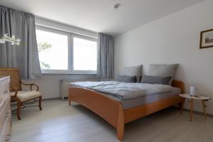 a bedroom with a bed and a chair and a window at Ferienwohnungen Riese - Ruhepol in Arnsberg