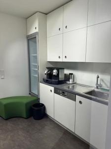 a kitchen with white cabinets and a green ottoman at Sleepsoon1 Nord in Cologne