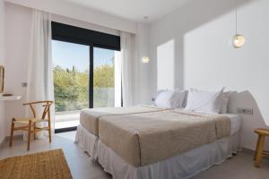a white bedroom with a large bed and a window at Elia Luxury Villa in Akrotiri +44 photos