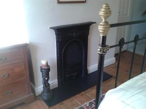 una chimenea negra en un dormitorio junto a una cama en Angate Cottage en Wolsingham