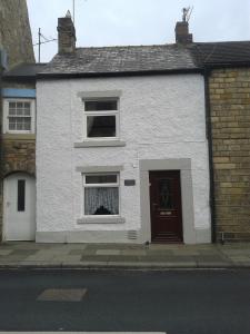 a white house with a window and a door at Angate Cottage in Wolsingham