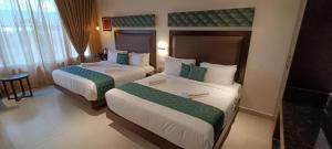 una camera d'albergo con due letti e un tavolo di Hotel Rameswaram Grand a Rāmeswaram