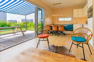 a living room with chairs and a kitchen with sliding glass doors at Huisje123 - Ecohuisjes Terschelling in Midsland