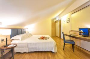 a hotel room with a bed and a desk and a television at Virgilio Grand Hotel in Sperlonga