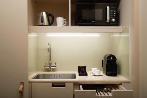 a small kitchen with a sink and a microwave at The Resident Victoria in London