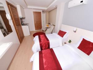 duas camas num quarto de hotel com lençóis brancos e vermelhos em Gazel Suites Downtown em Istambul
