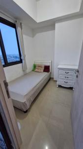 a bedroom with a bed and a window and a dresser at Little Tiny Kingdom Apartemen Jakarta Living Star in Jakarta