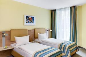 a hotel room with two beds and a window at IntercityHotel Düsseldorf in Düsseldorf