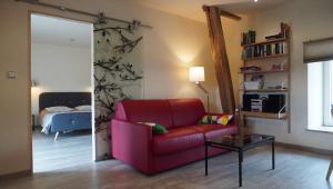 a living room with a red chair and a bed at La Closerie in Marcenay