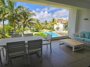 a living room with a table and chairs and a pool at Luxury 3 Bedroom Apartment Sea View Azuri Estate in Roches Noires