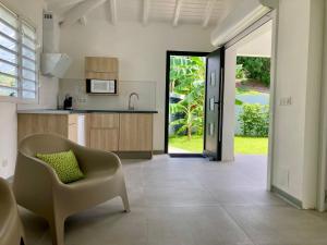 Una sala de estar con una silla y una cocina. en Villas Makandja - plage à 3 min à pied, piscines et jardins privés, en Sainte-Anne 27 fotos más
