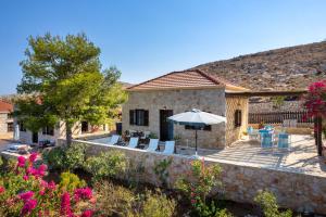 a house with an umbrella and chairs and flowers at Villa Ftenagia in Halki