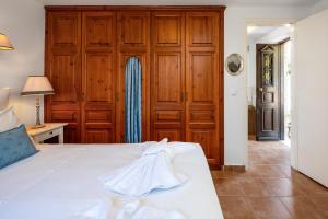 a bedroom with a white bed and wooden cabinets at Villa Ftenagia in Halki