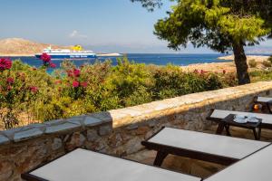 a stone wall with benches and a boat in the water at Villa Ftenagia in Halki
